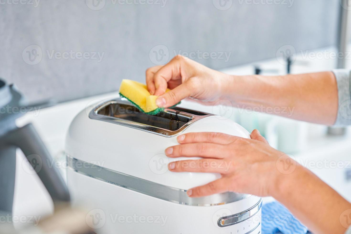 mujer limpiando parrilla o tostadora en la cocina foto