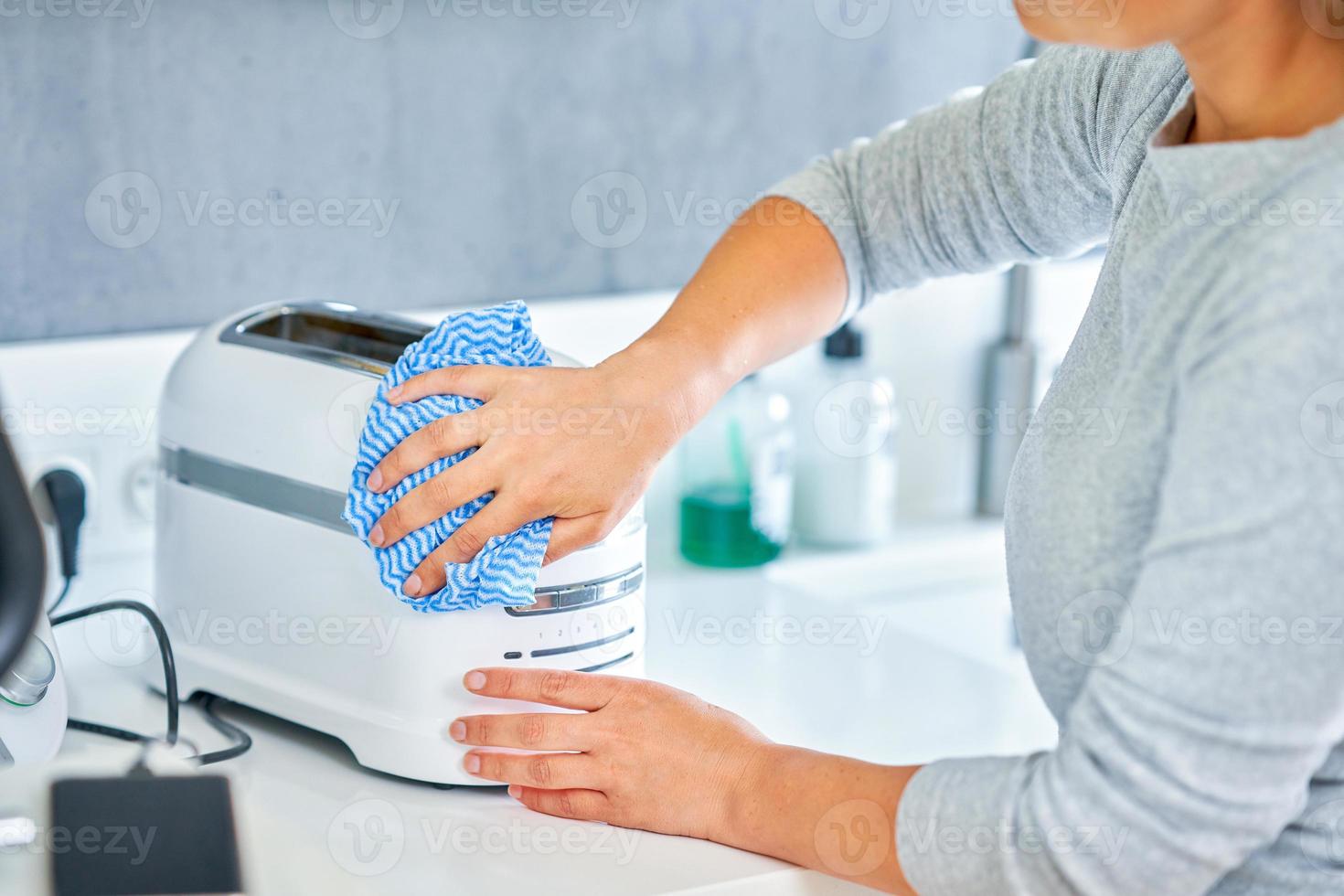 mujer limpiando parrilla o tostadora en la cocina foto