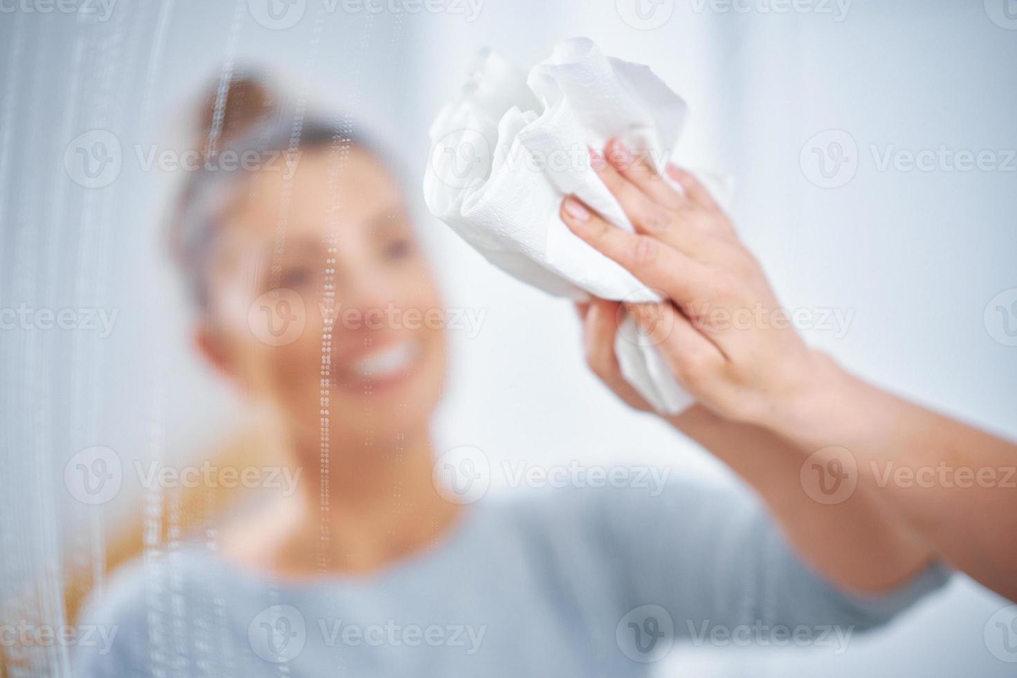 foto de una mujer limpiando la ventana del espejo