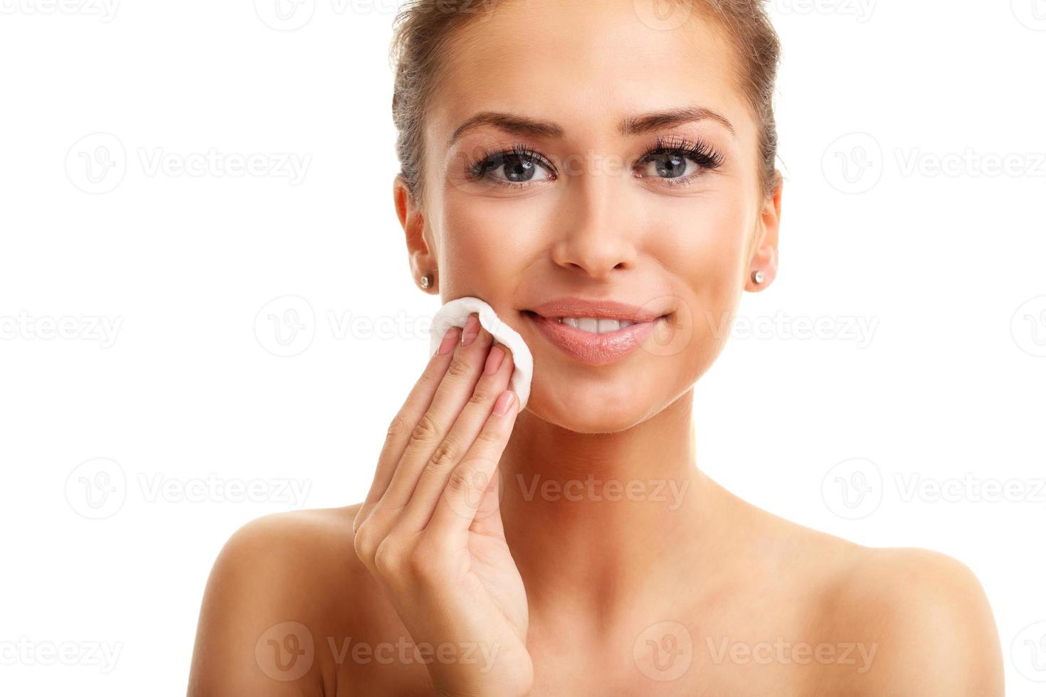 Portrait of adult woman smiling and using cotton pad against white background photo