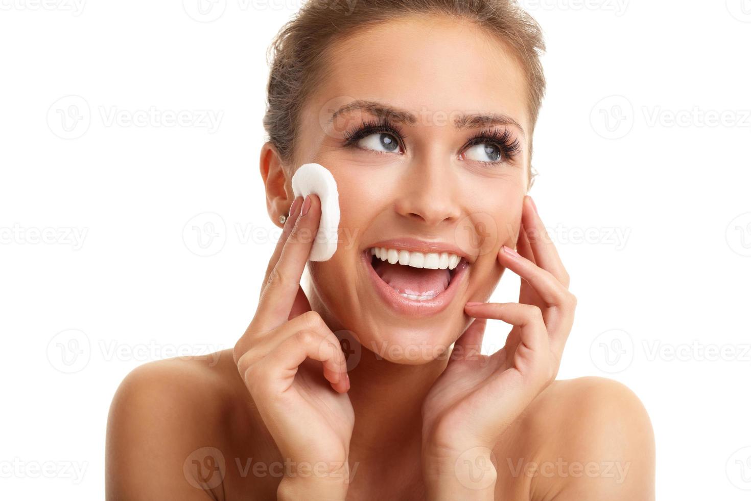 Portrait of adult woman smiling and using cotton pad against white background photo