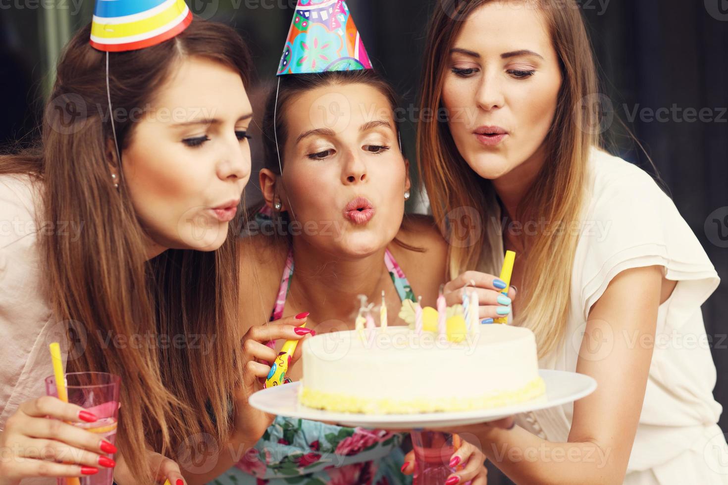 Group of friends blowing candles on cake photo