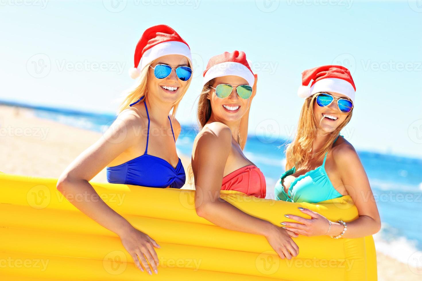 grupo de chicas con sombreros de santa divirtiéndose en la playa foto