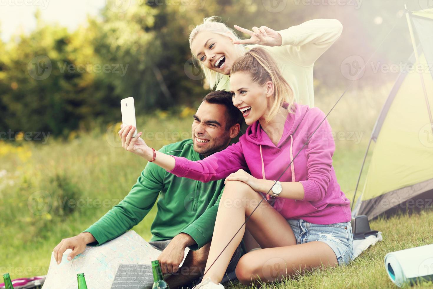 Group of friends camping in forest and taking selfie photo