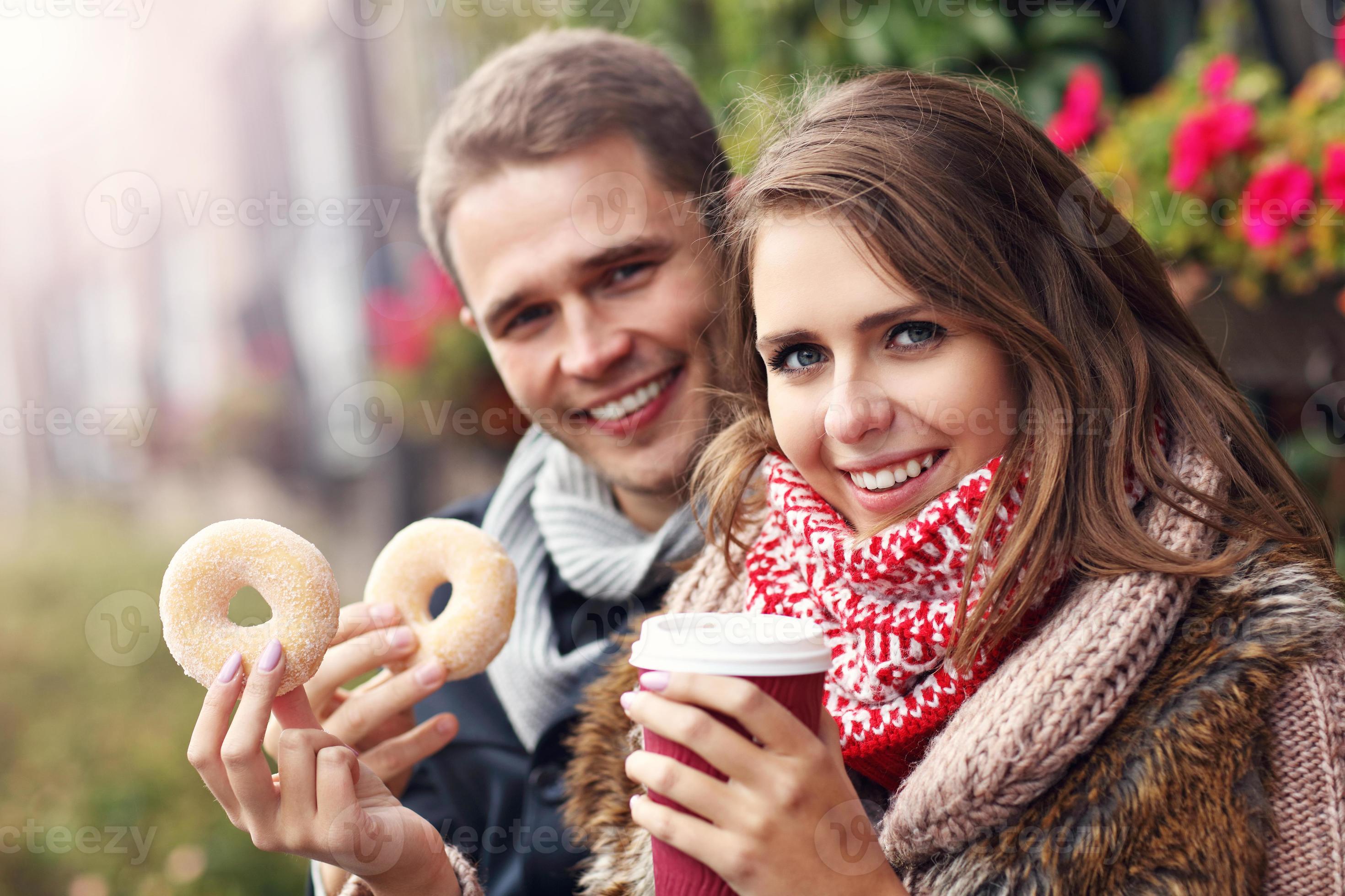 Young couple sitting on bench with coffee and donuts 15884228 Stock