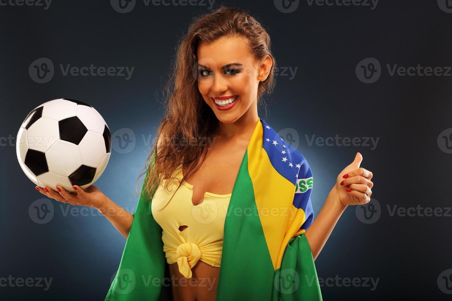 feliz hincha brasileño animando con bandera y fútbol foto