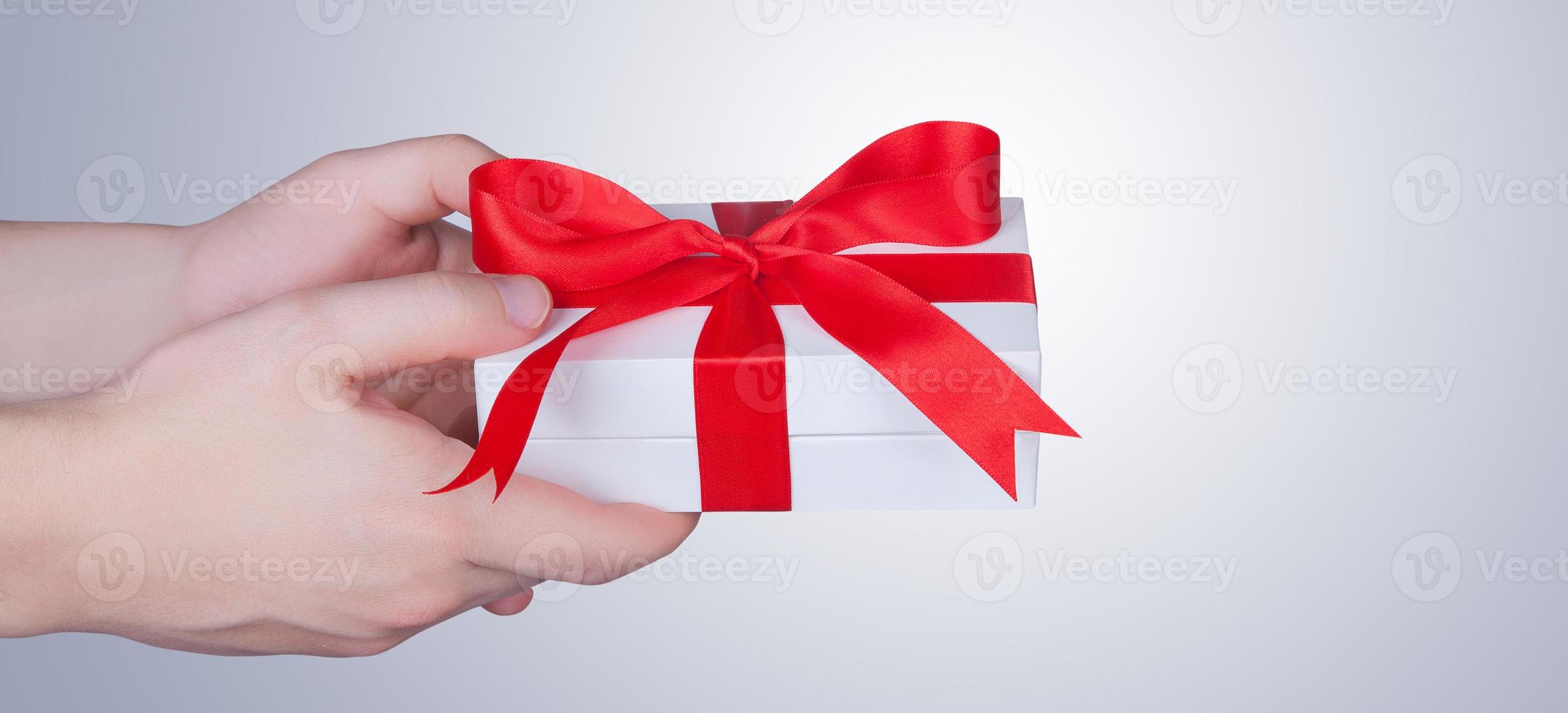 Mujer sosteniendo una caja de regalo en un gesto de dar. foto