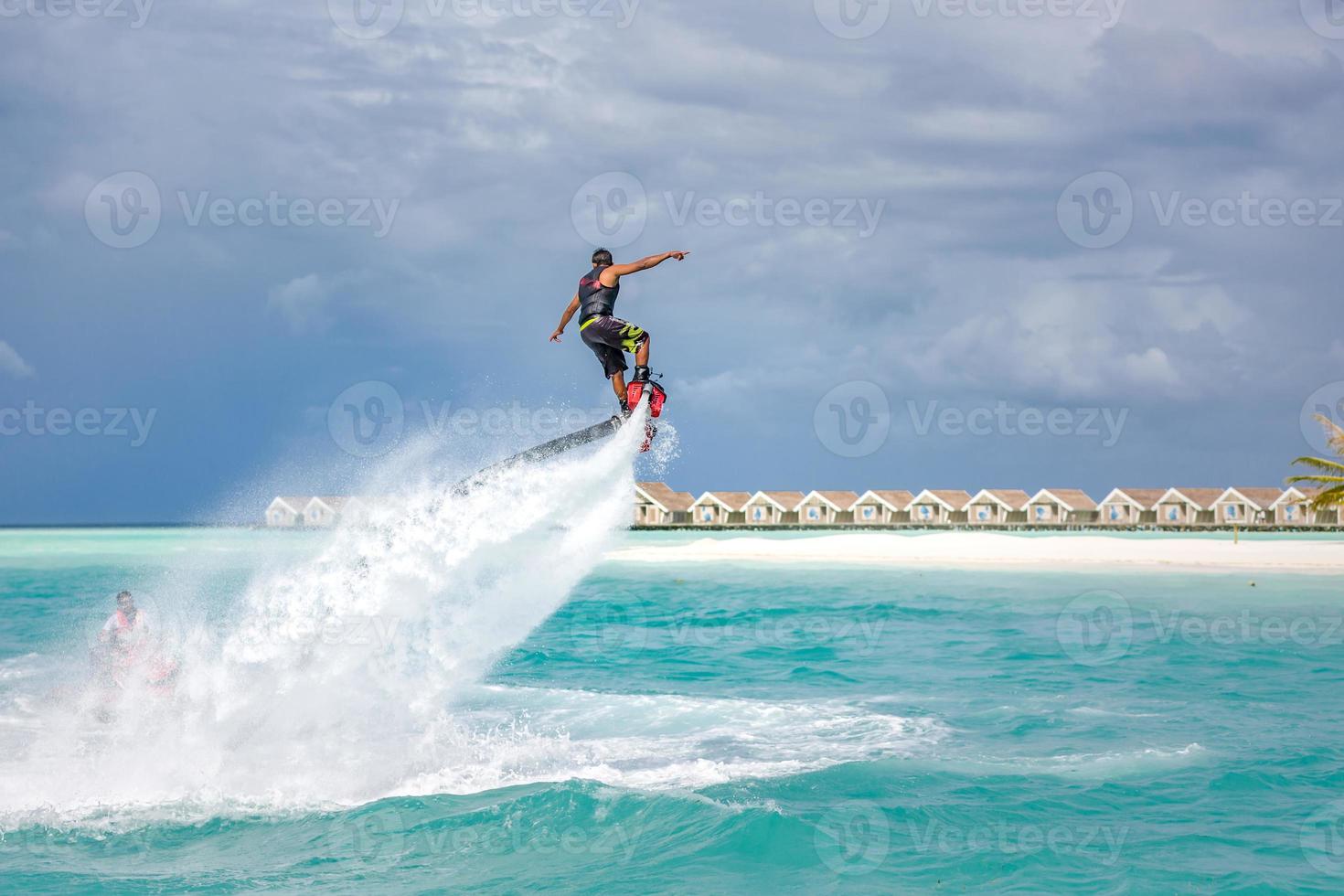 Water extreme sport, summer sea and tropical weather with outdoors active people enjoying water sports. Fly board, surfing in ocean, fun and summer recreational activity. Flyboarding and seariding photo