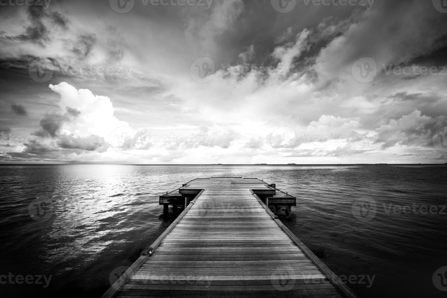 Embarcadero de madera monocromo en blanco y negro sobre mar poco profundo. concepto de tristeza sola caminar a ninguna parte sin destino y nadie ayuda a guiar el camino foto