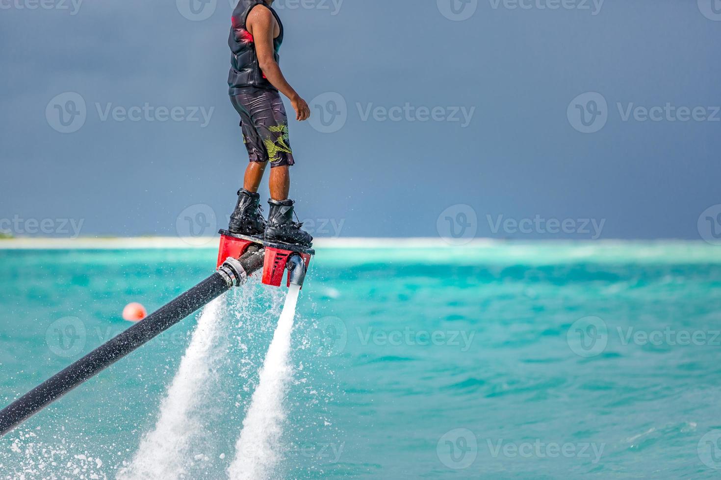 Water extreme sport, summer sea and tropical weather with outdoors active people enjoying water sports. Fly board, surfing in ocean, fun and summer recreational activity. Flyboarding and seariding photo