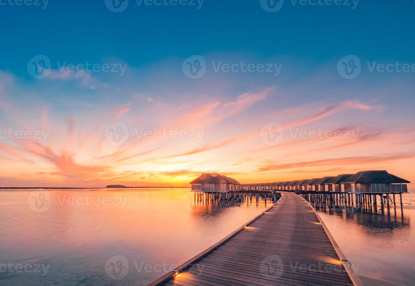 puesta de sol en la isla de maldivas. resort de bungalows de agua en la playa de las islas. océano índico, maldivas. hermoso paisaje de puesta de sol, resort de lujo y cielo colorido. puesta de sol de playa artística bajo un cielo maravilloso foto