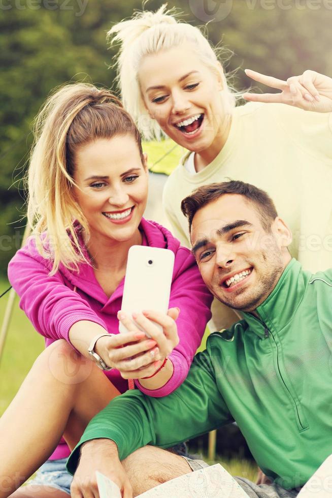 Group of friends camping in forest and taking selfie photo