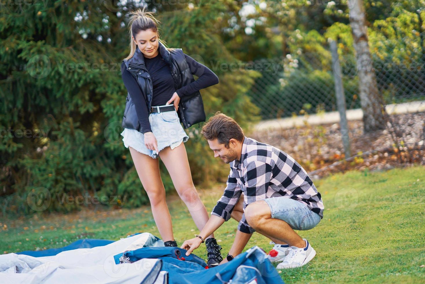 Young nice couple having fun on camping setting up tent photo