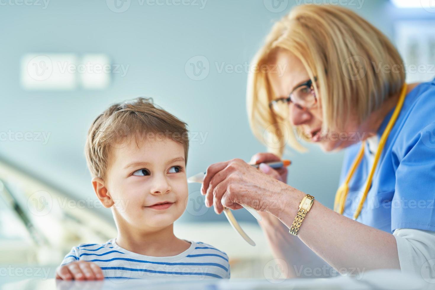 Pediatrician doctor examining little kids in clinic ears check photo