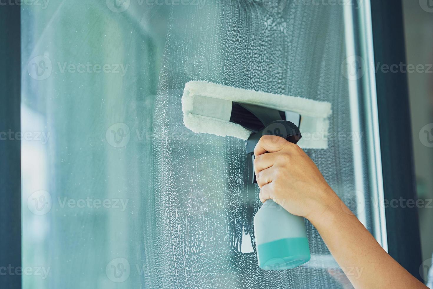 Young woman cleaning window int he kitchen photo