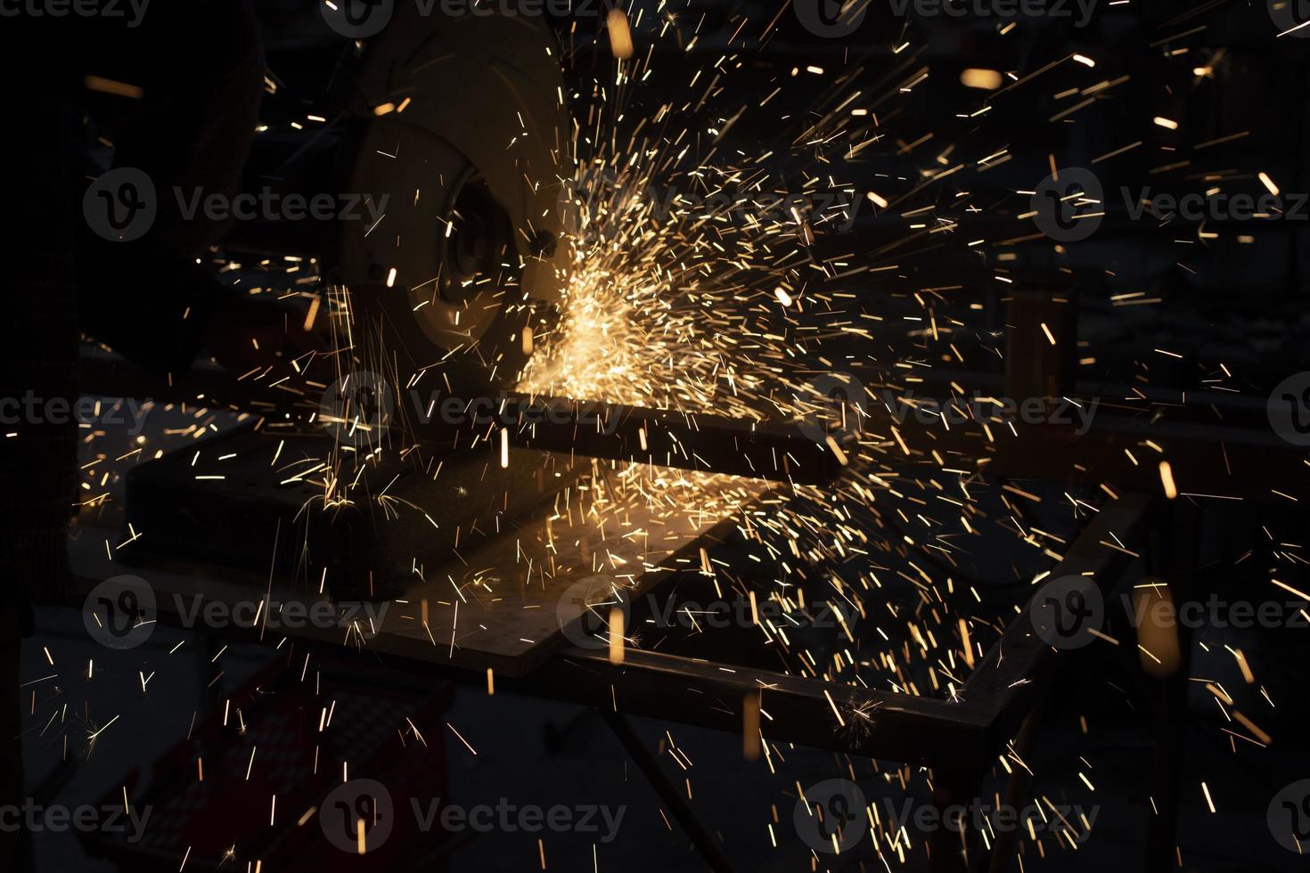 Lots of sparks from cutting metal in dark. Lights fly in different directions. Industrial background. photo