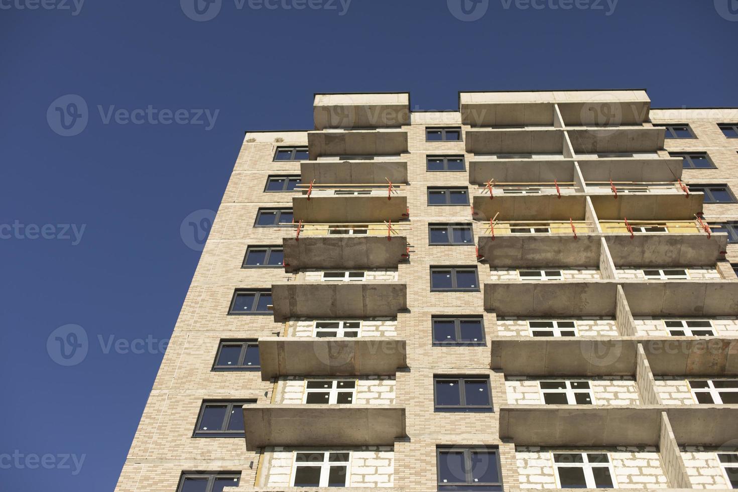 Facade of building. Unfinished house. Windows in new multi-storey building. Plastic windows on street. photo