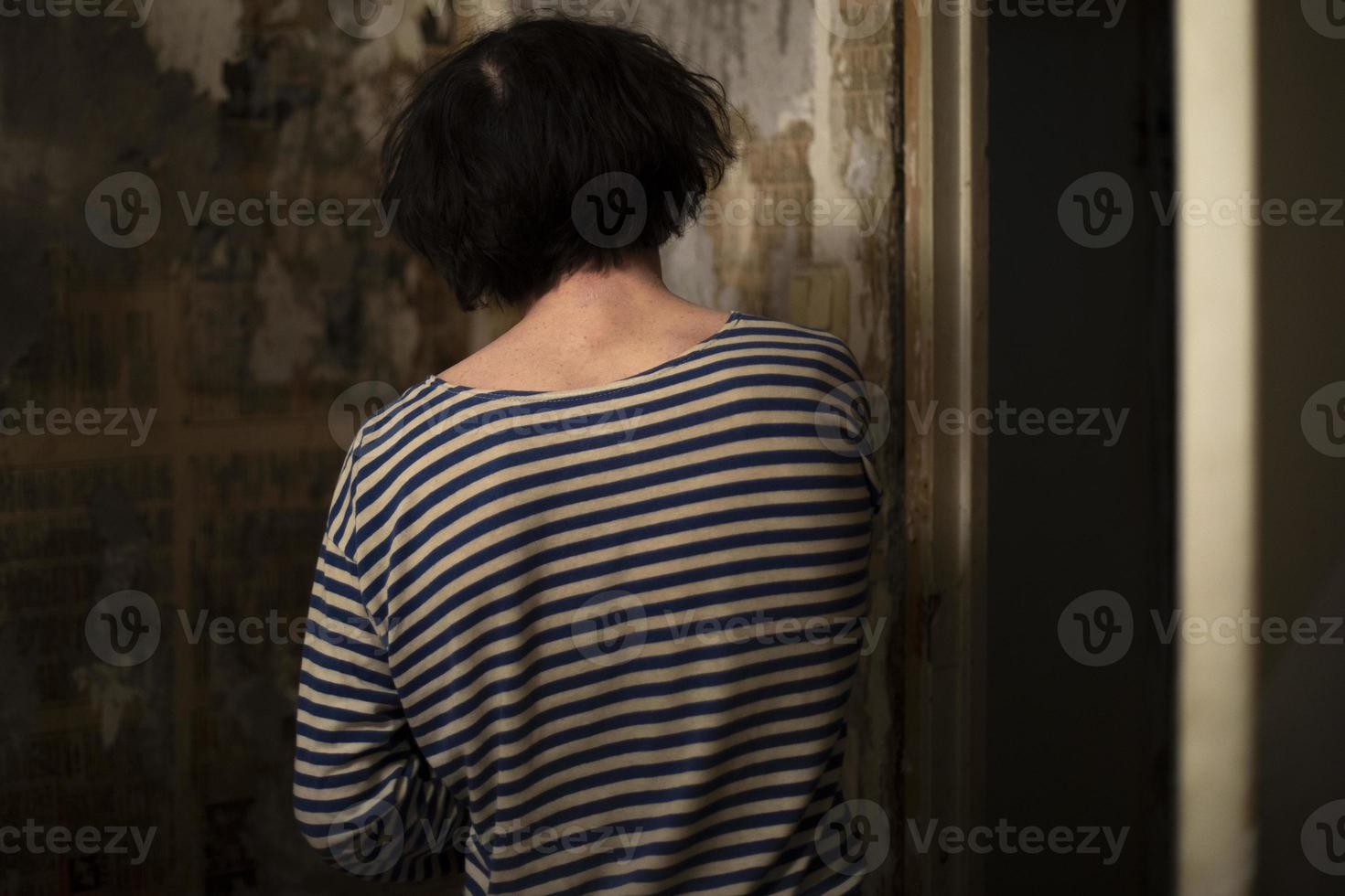 Guy makes repairs in room. Man in striped jacket. Person repairs wall. Wallpaper gluing in apartment. photo