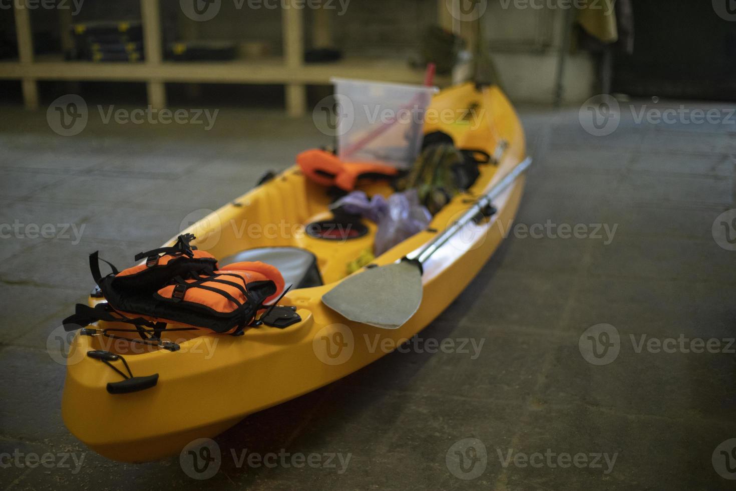 Yellow boat made of plastic. Canoe in garage. Sports equipment. Preparation for hike. photo