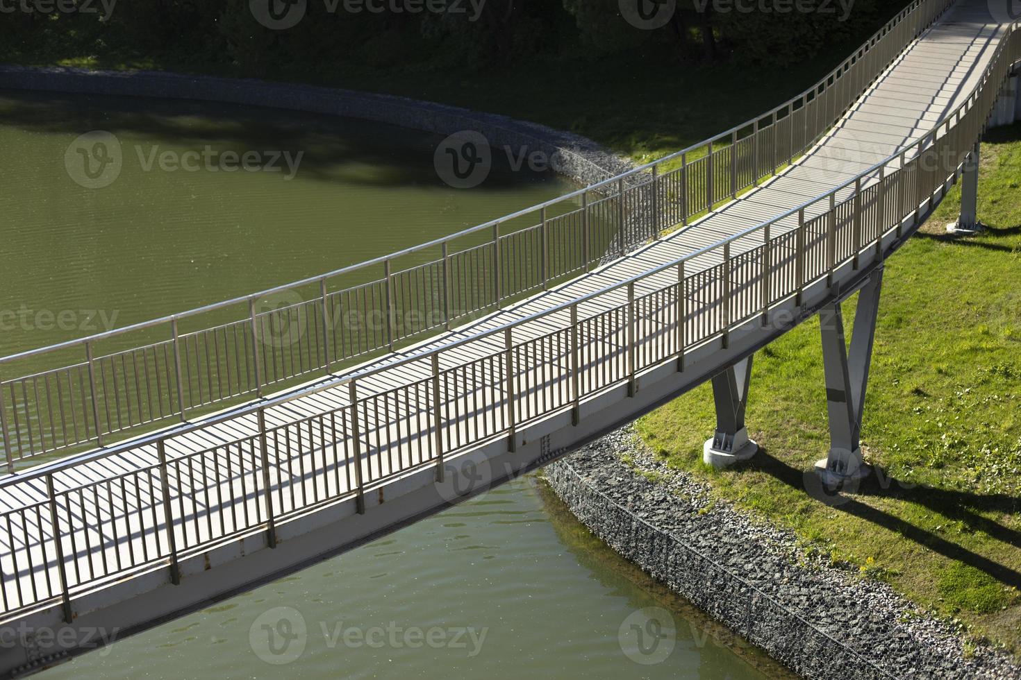 Pedestrian bridge on water. Bridge with railings. Details of park in city. photo