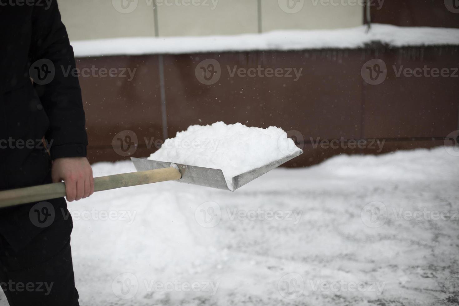 Snow removal on street. Shovel for track cleaning. Man cleans up yard. photo