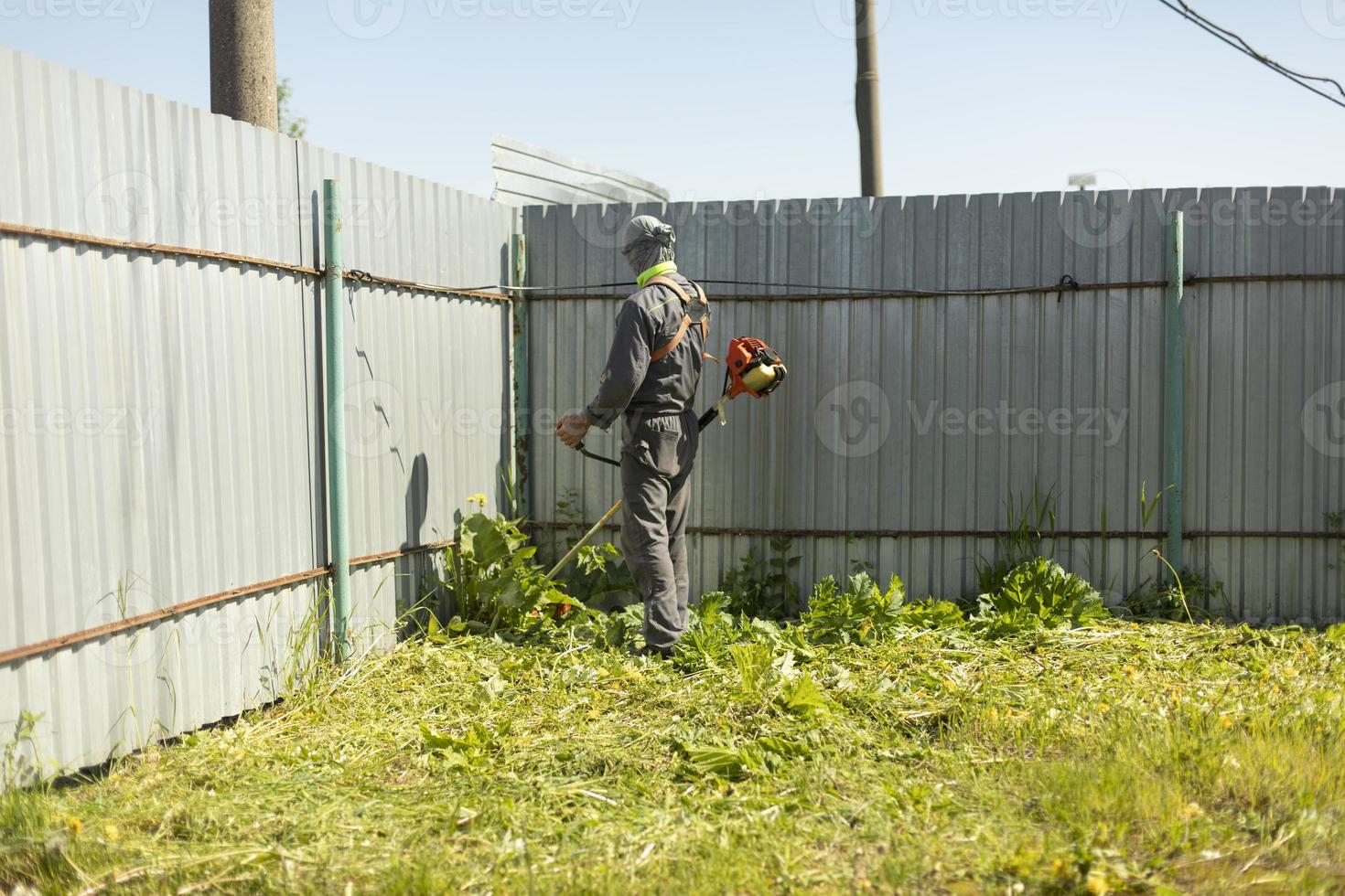 Lawn mower mows grass. Worker cuts plants. photo
