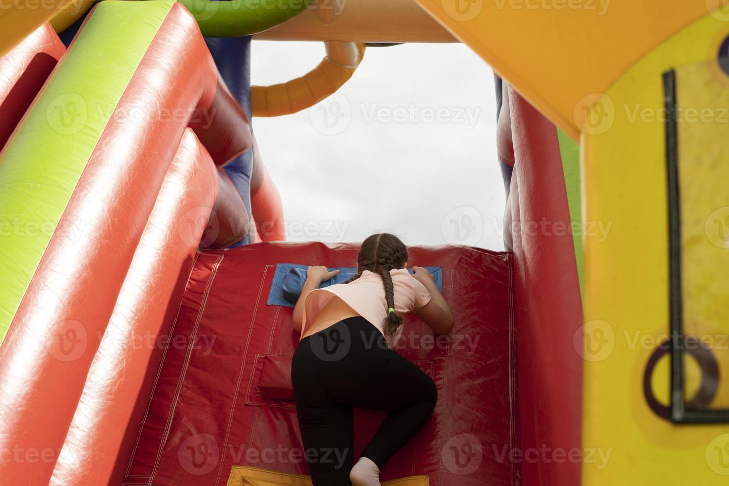 Child on slide. Inflatable slide for children. Baby climbs up. Play area in summer. photo