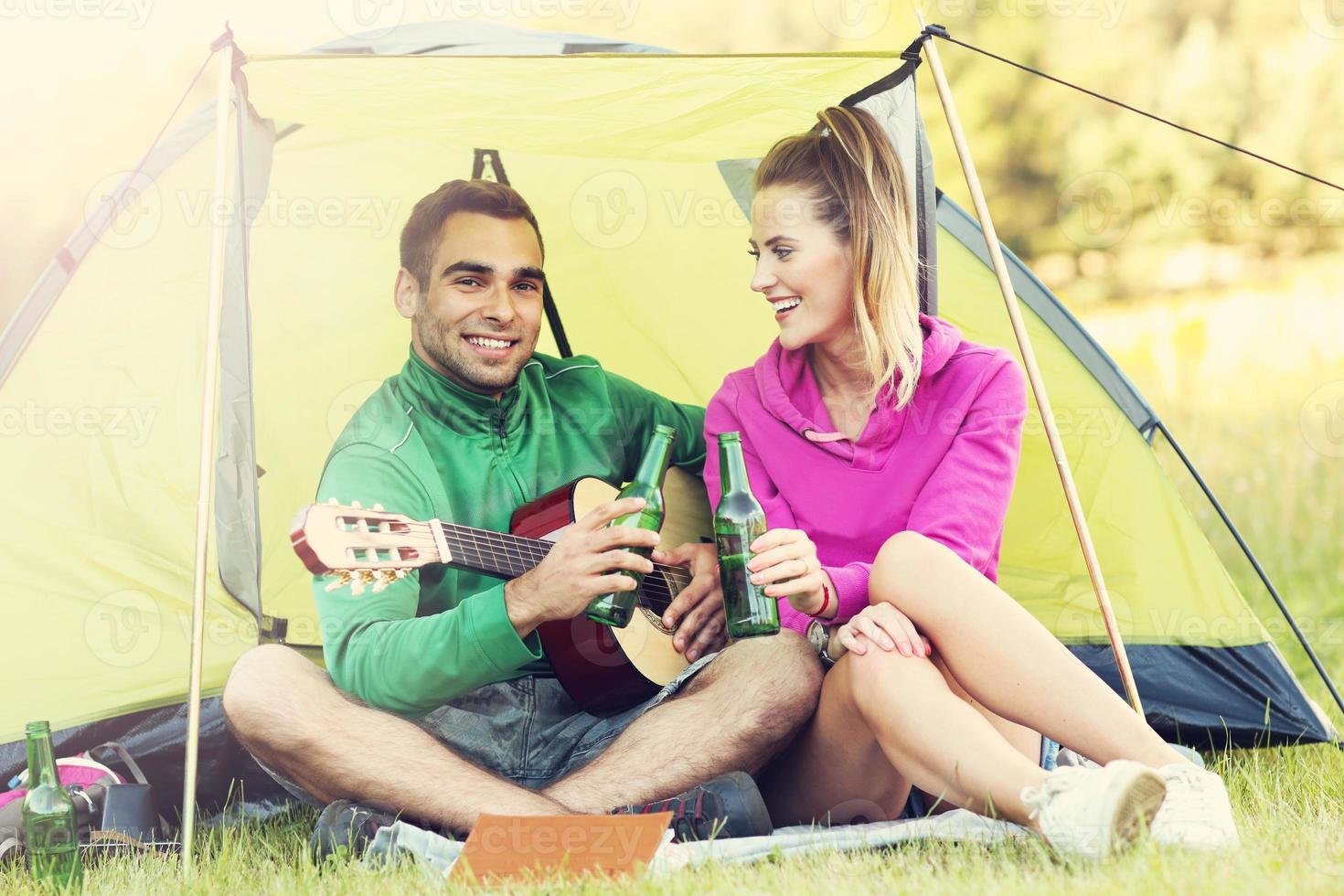 Couple camping in forest and playing guitar photo