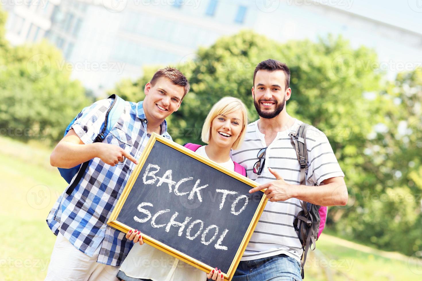 Group of students holding a back to school blackboard in the park photo