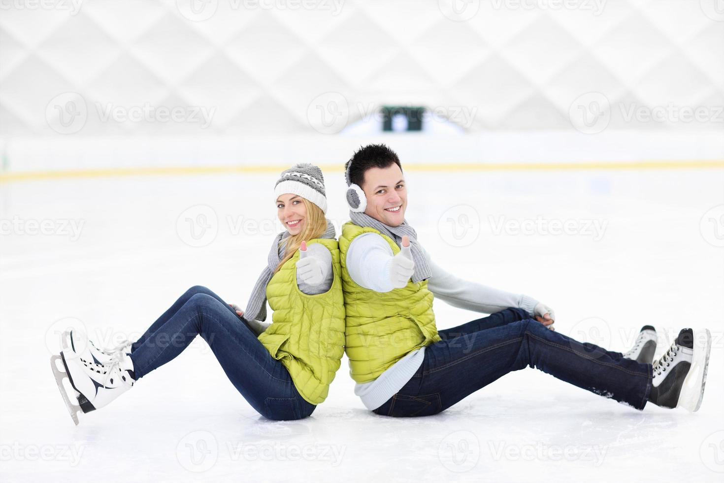 pareja alegre sentada en la pista de patinaje foto