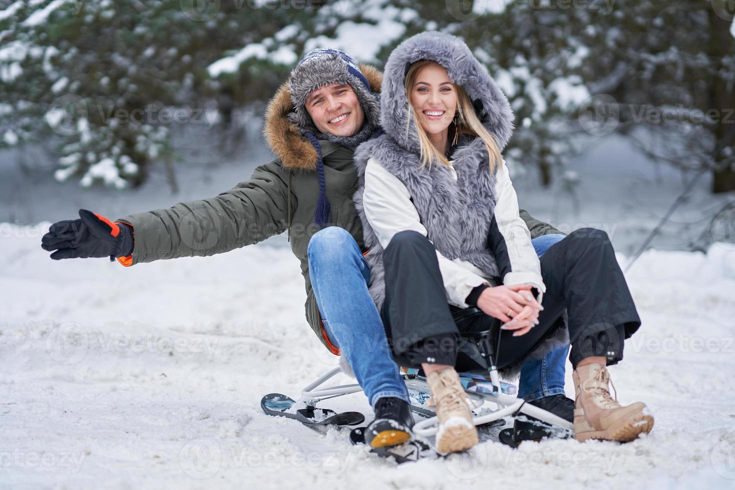 Couple having fun with sledge on snow in winter photo
