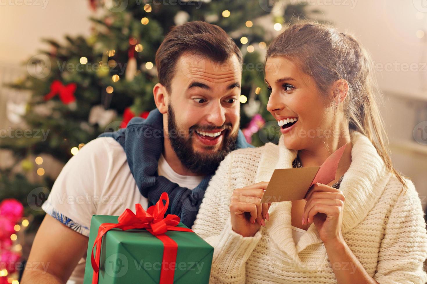 pareja joven con presente sobre el árbol de navidad foto