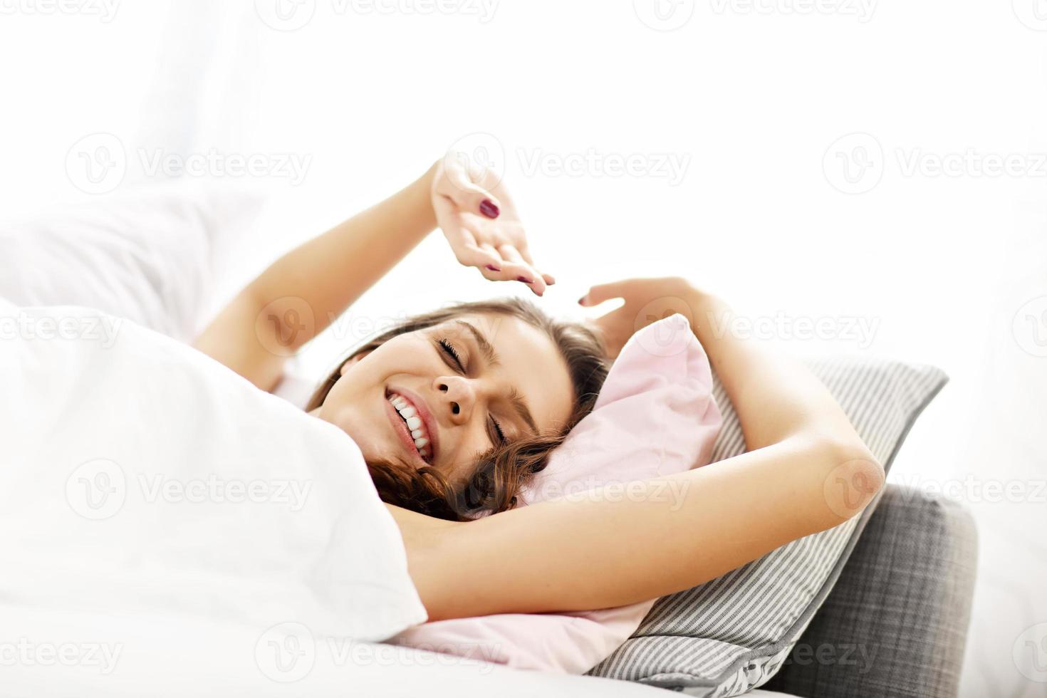 mujer joven estirandose en la cama foto