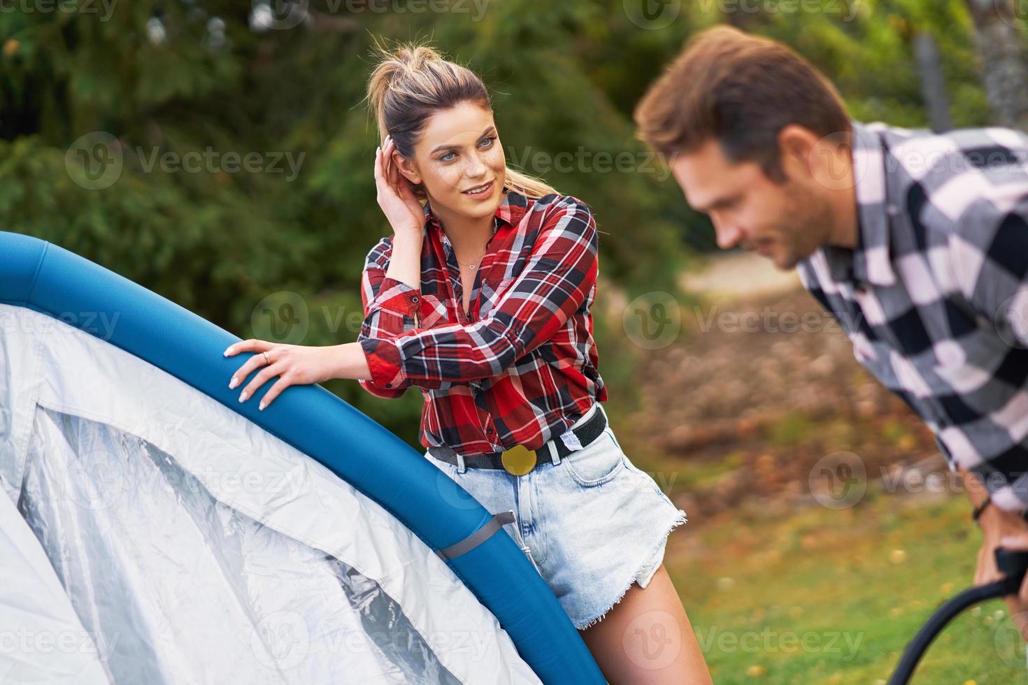 Young nice couple having fun on camping setting up tent photo