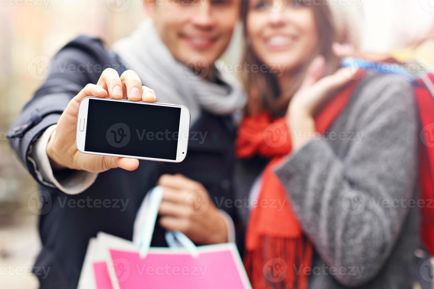 Midsection of couple shopping in the city with smartphone photo