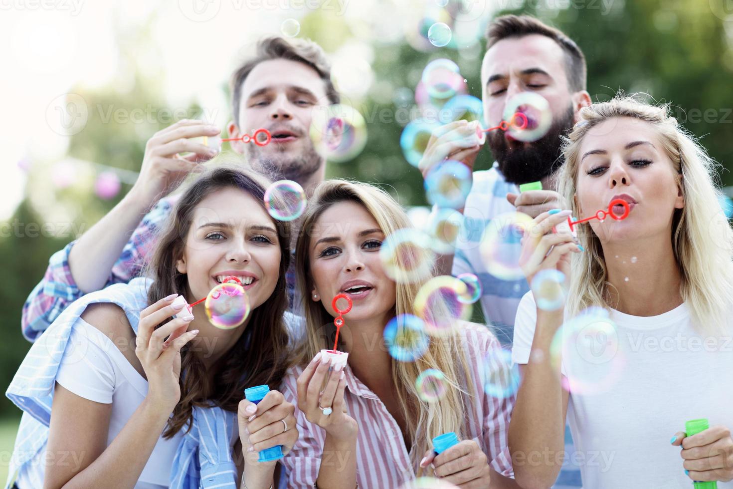 Happy group of friends blowing bubbles outdoors photo