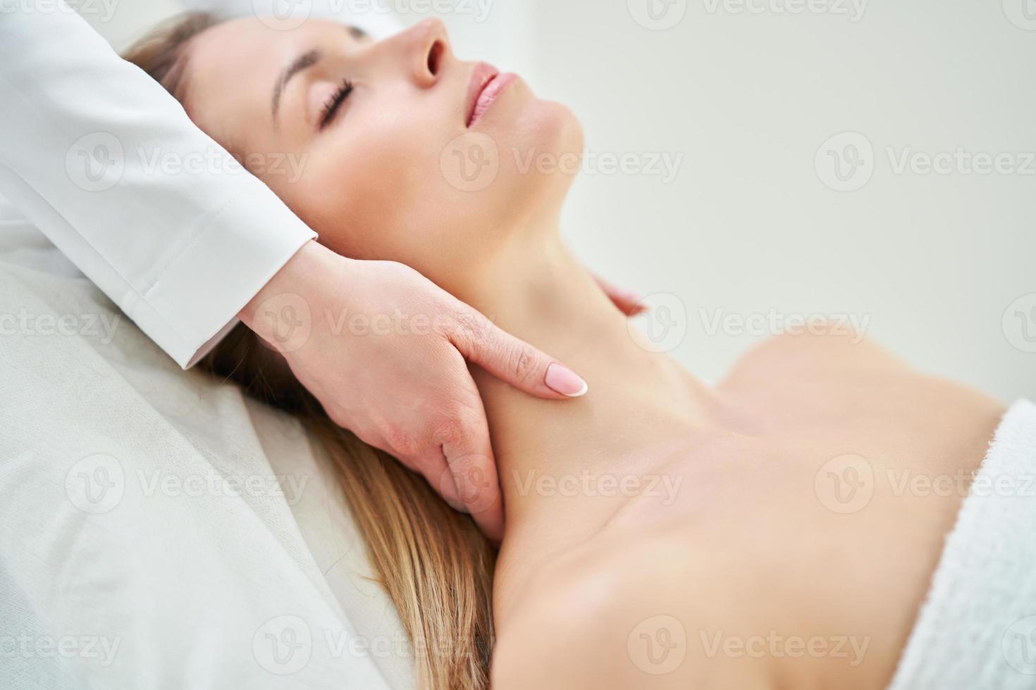 Young nice woman having face massage in spa photo