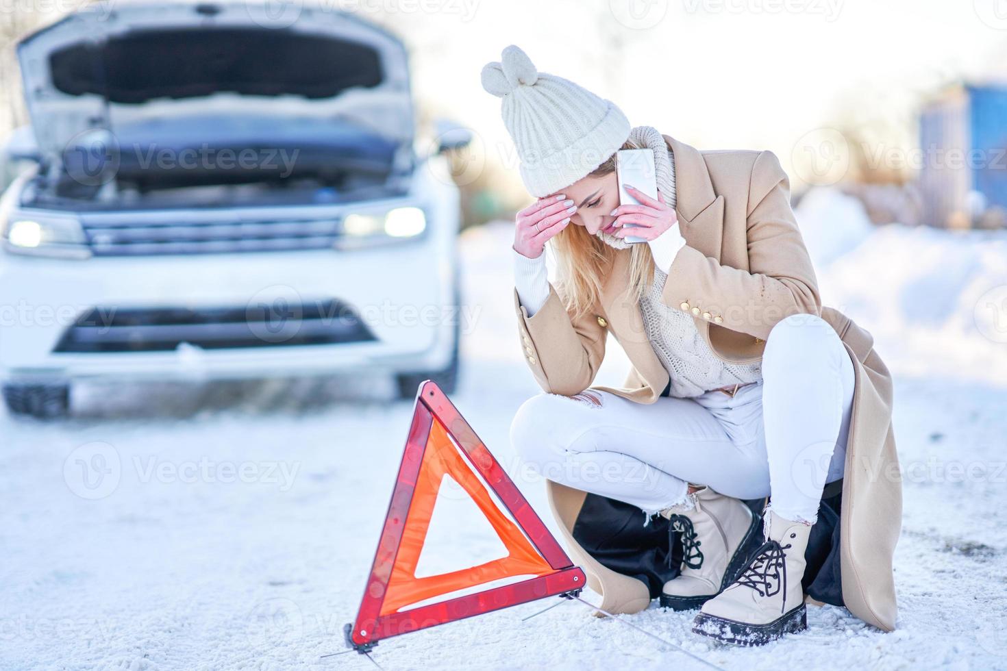 mujer joven que tiene problemas con el coche en invierno foto