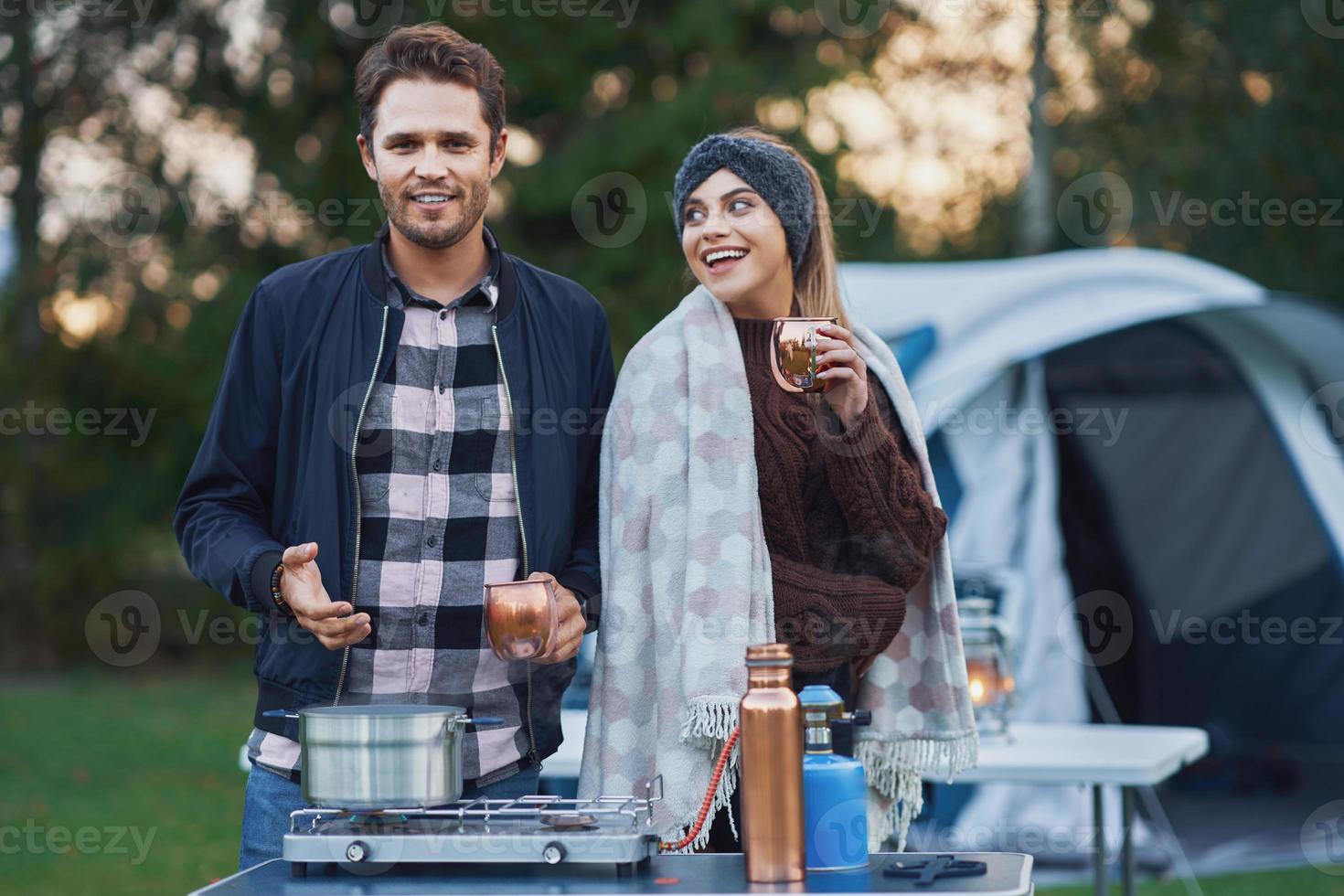 Young nice couple having fun on camping while cooking and eating photo