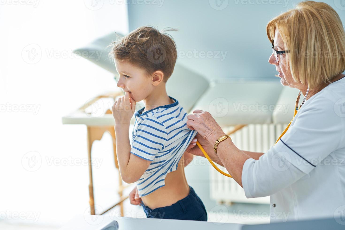 Pediatrician doctor examining little kids in clinic photo