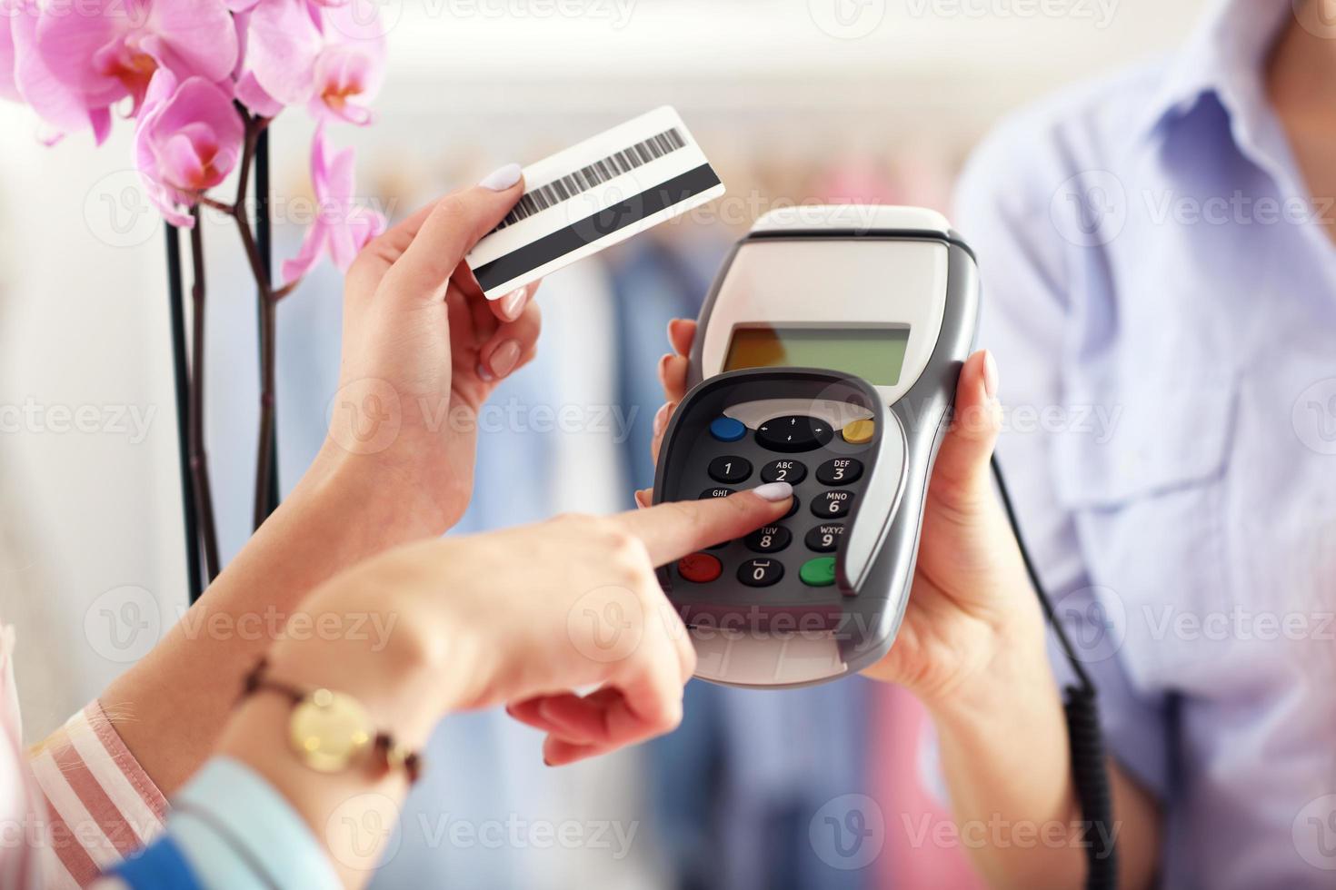 Closeup mid section of female customer paying in shop with credit card photo