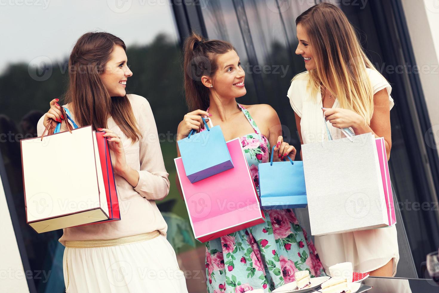 Three friends chatting in cafe with shopping bags photo