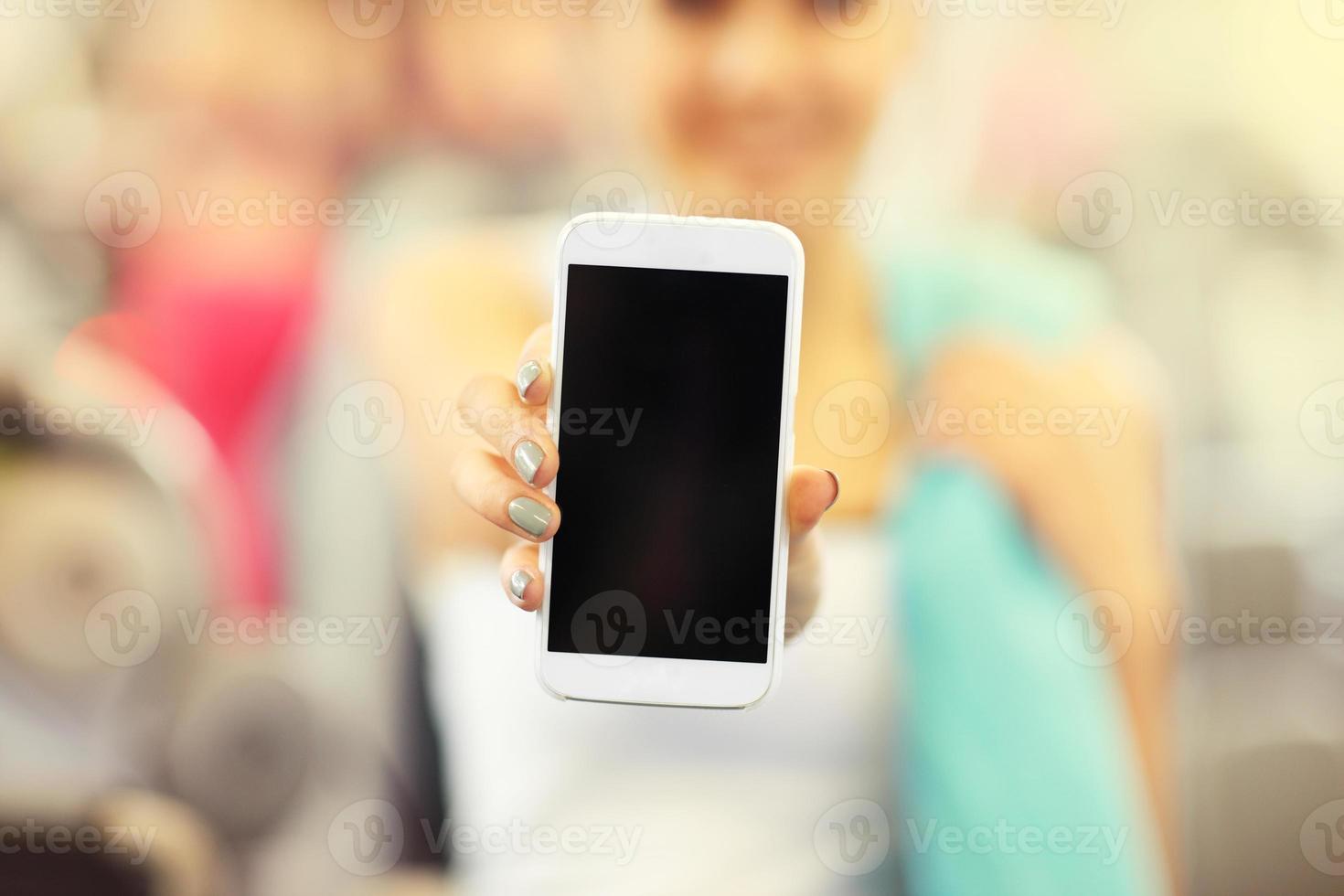 Woman holding smartphone in gym photo