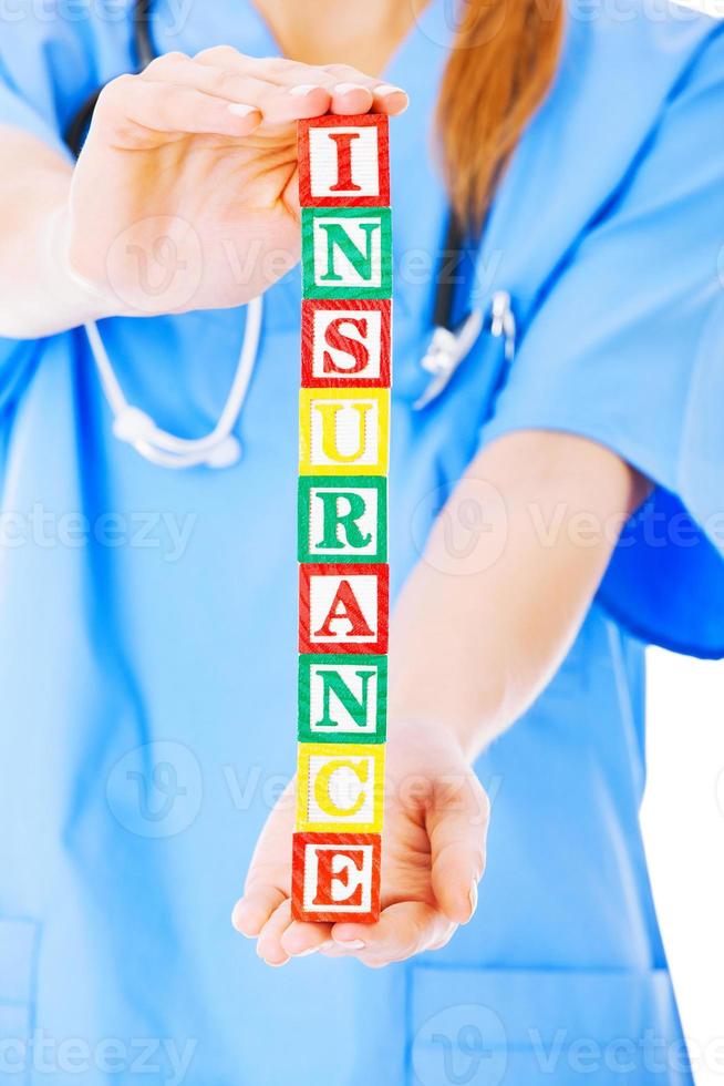 Nurse Holding Blocks Spelling Out Insurance Over White Background photo