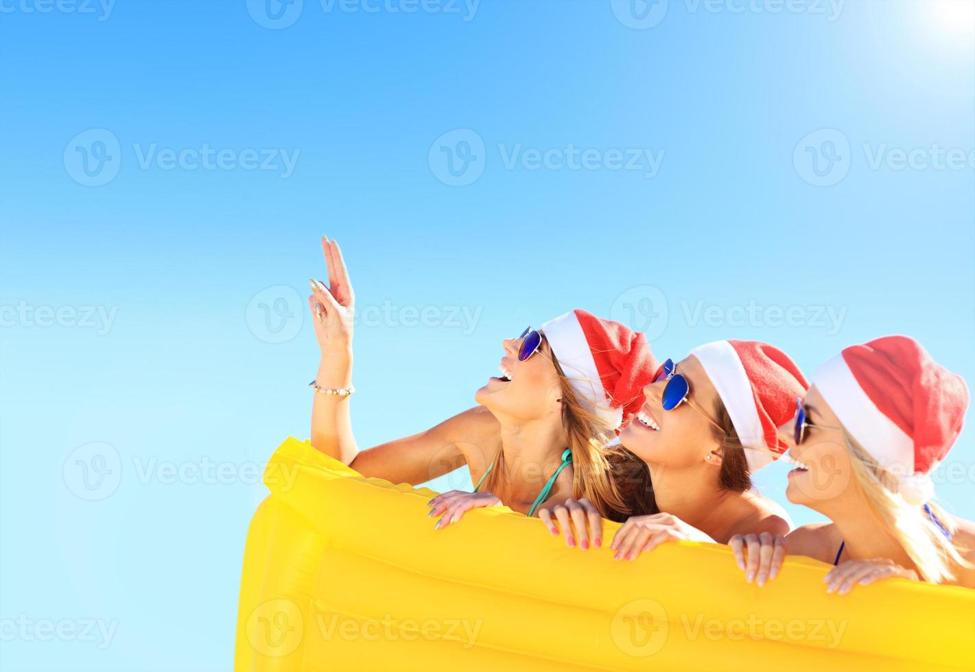 Group of girls in Santa's hats having fun on the beach photo