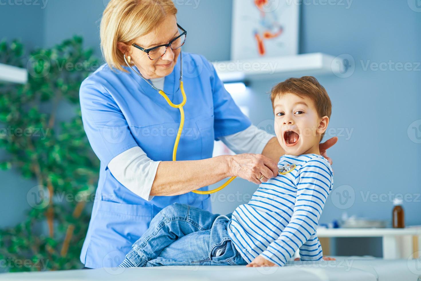Pediatrician doctor examining little kids in clinic photo