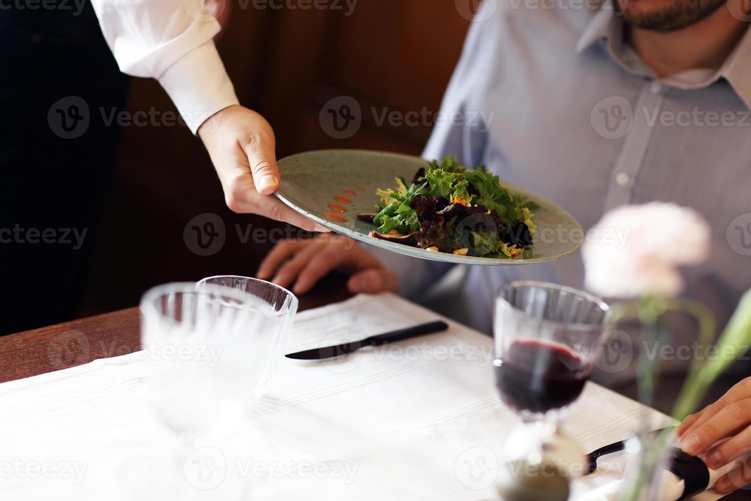 Romantic couple dating in restaurant being served by waiter photo