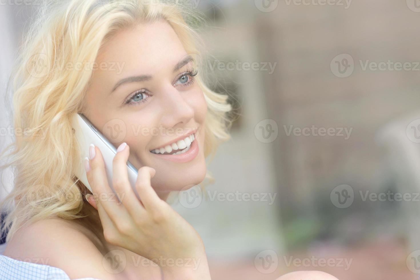 Young pretty woman sitting in the window and talking on phone photo