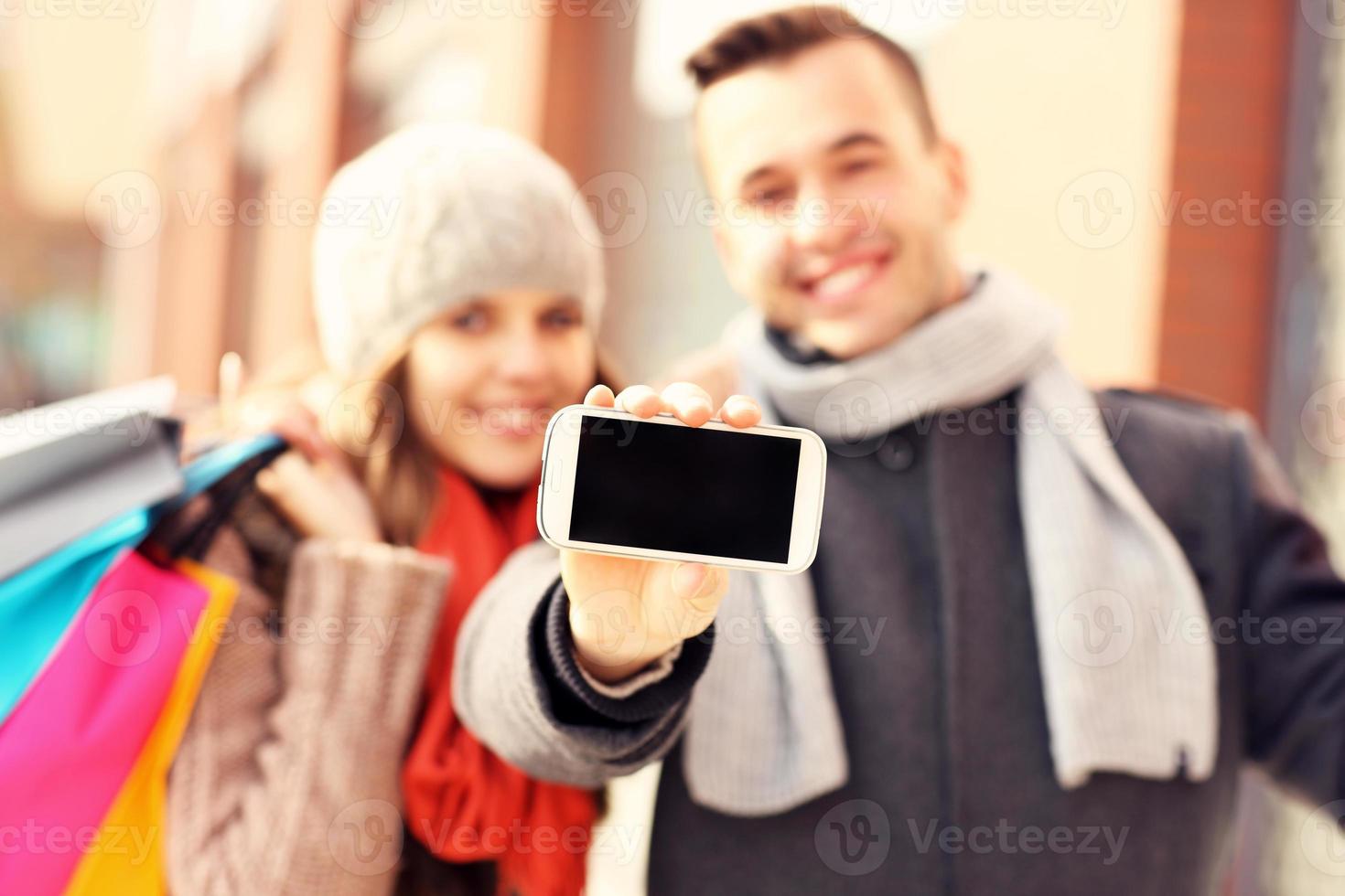 Happy couple showing smartphone while shopping photo