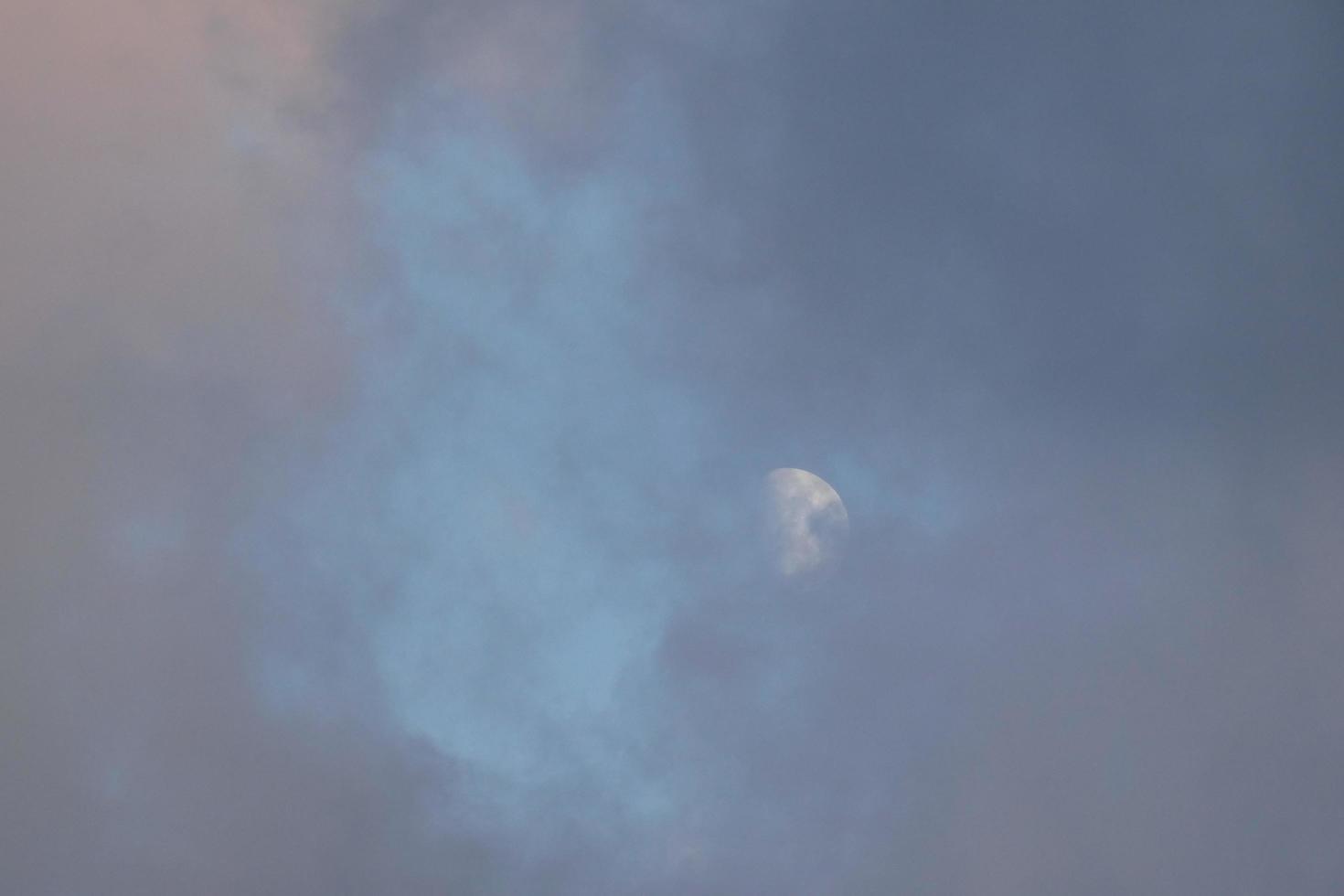 Near-full moon, seen through the clouds at sunset. photo